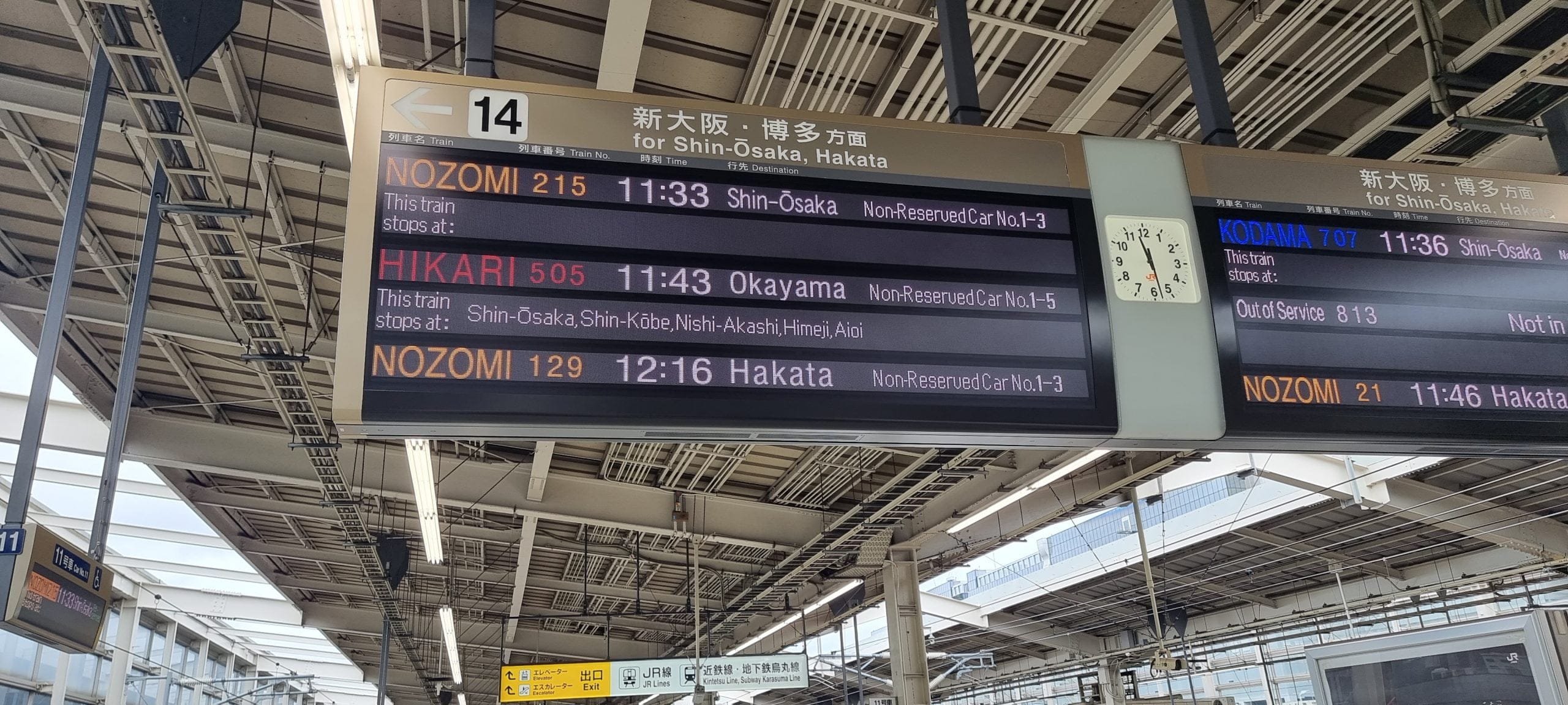 overhead gantry sign on bullet train platform displaying shinkansen times.