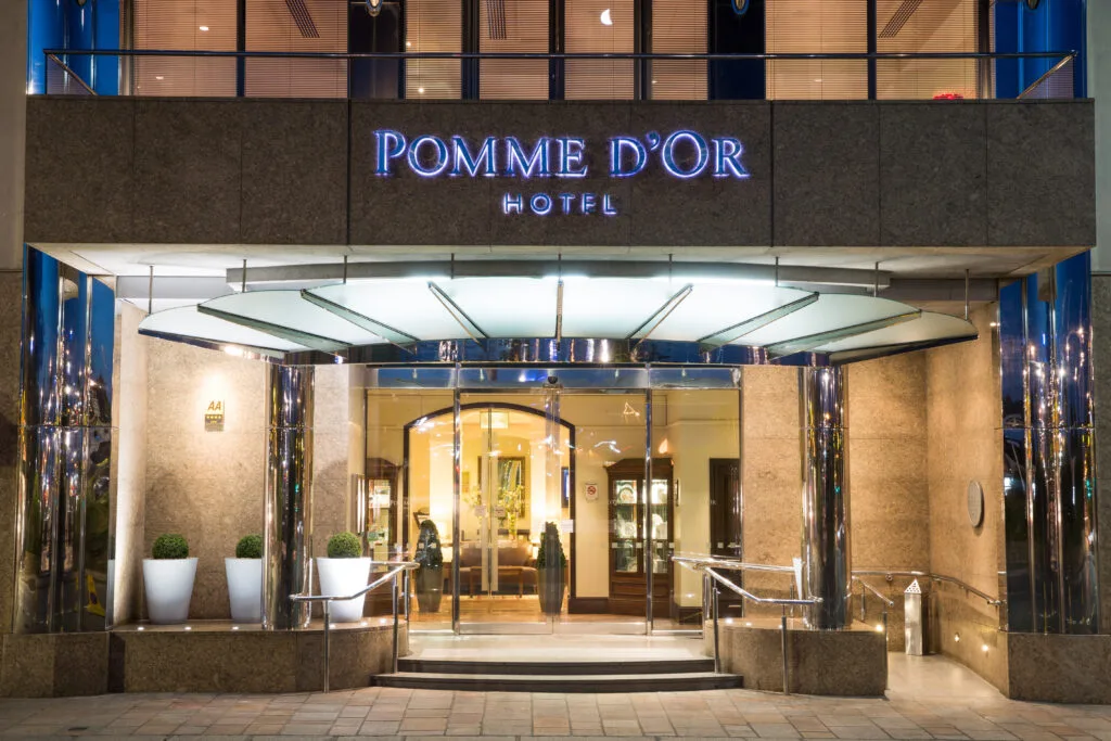 Main entrance of the Pomme d'Or Hotel in St Helier, Jersey, illuminated at night with the hotel signage clearly visible.