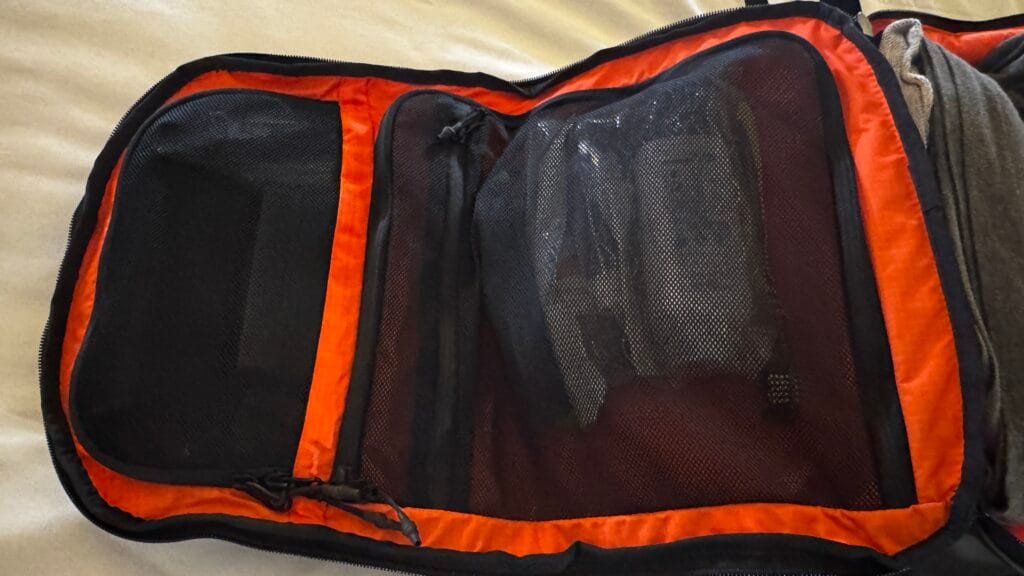 Inside view of 30L hybrid backpack showing orange lining and internal mesh organiser pockets