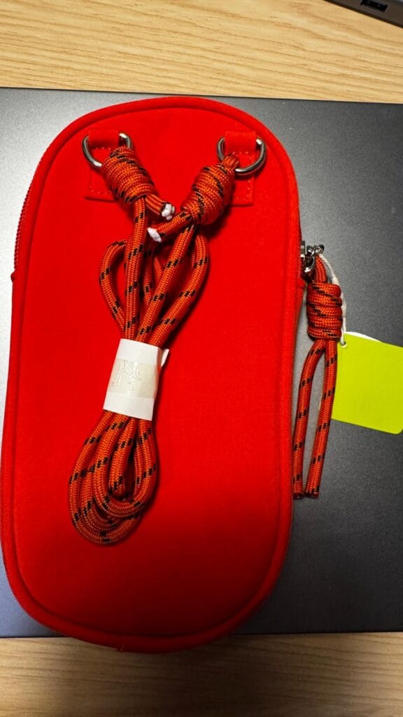 Back of the red Vooglam crossbody phone bag showing the shoulder strap and metal rings.
