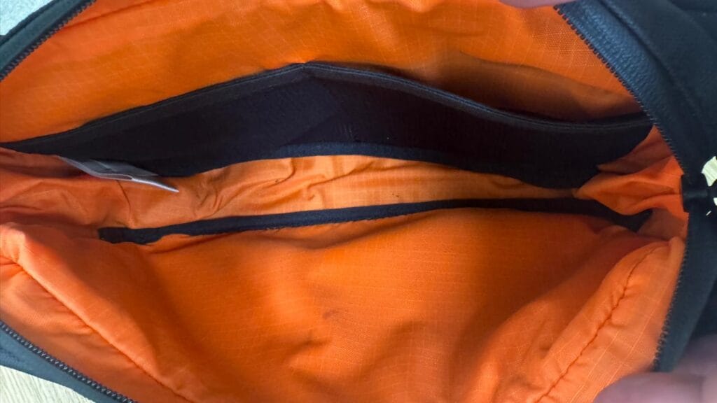 Interior compartment of the sling bag with orange lining