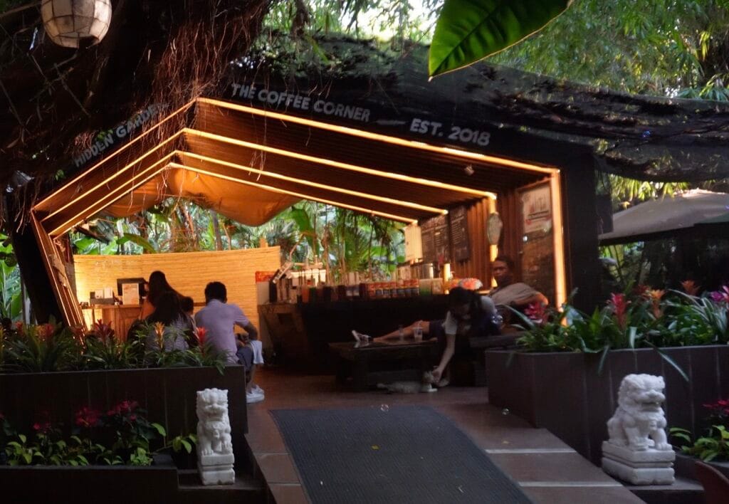 Hidden Garden The Coffee Corner outdoor cafe with warm lighting, seating area and lush greenery in a tropical garden setting