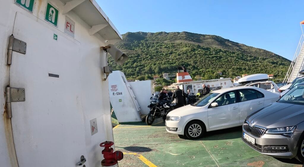 Cars and motorcycles parked on the open vehicle deck of the Kamenari Lepetane ferry