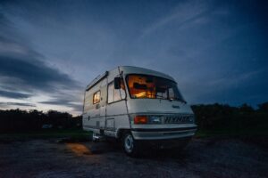 RV Motorhome parked off grid at dusk with its interior lights on